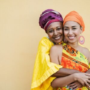 Happy mother and daughter with traditional african dresses smiling on camera